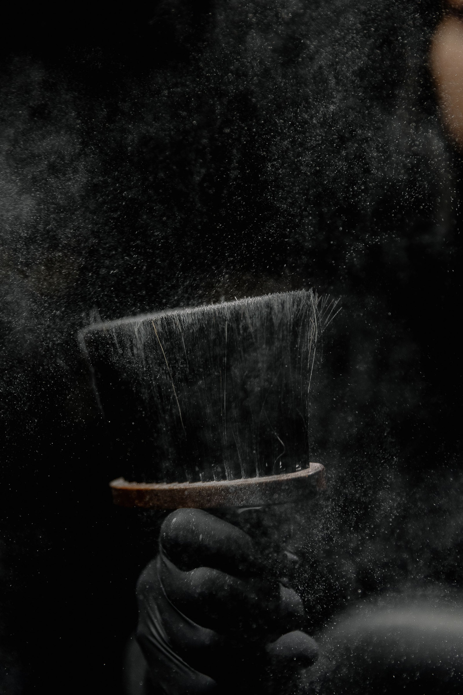 A neck brush, talc caught in the air against black