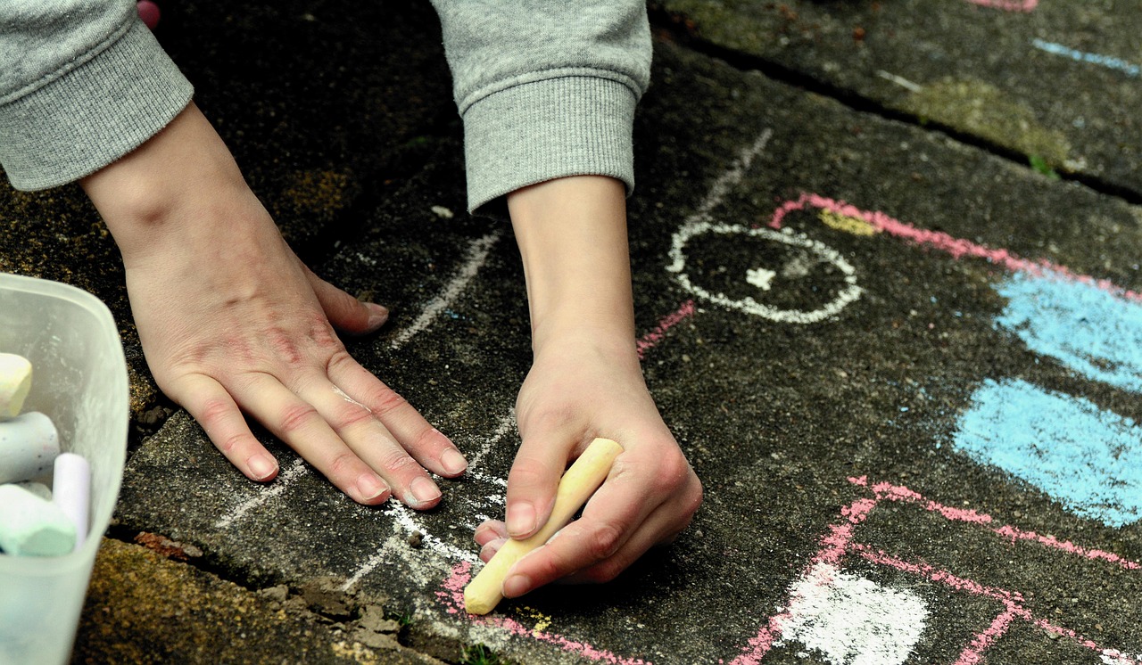 Small hands drawing with chalk on the pavement
