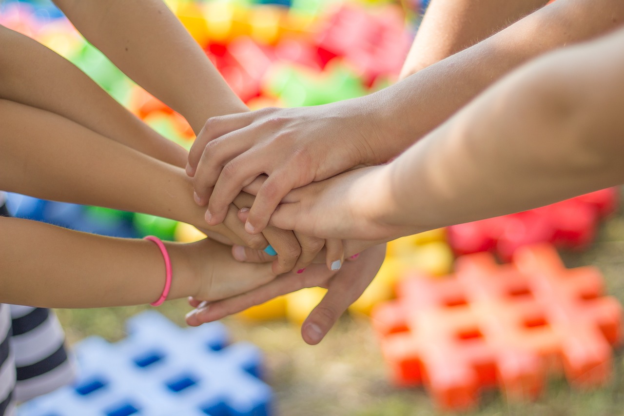 Children's and adults' hands stacked together over colourful toys