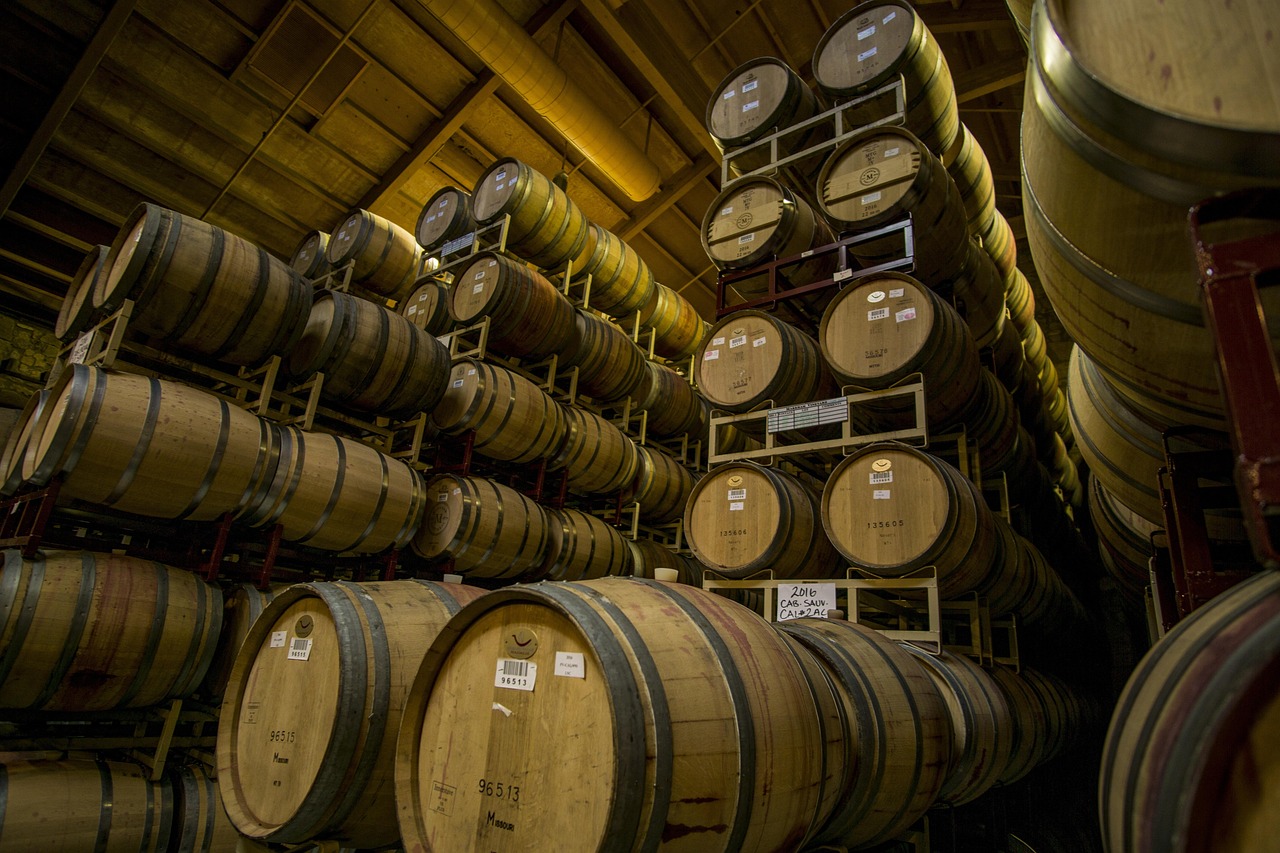 Stacked oak barrels in a dim timber-roofed cellar