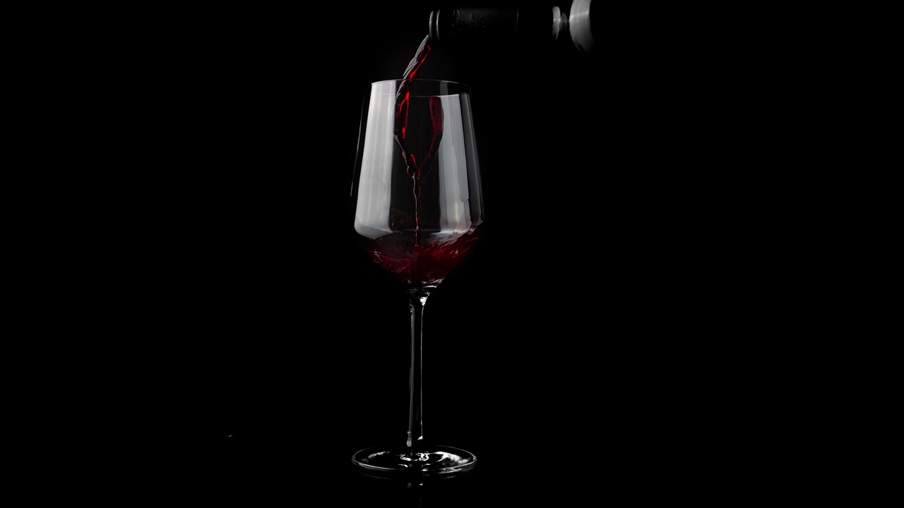 Red wine being poured into a glass against black