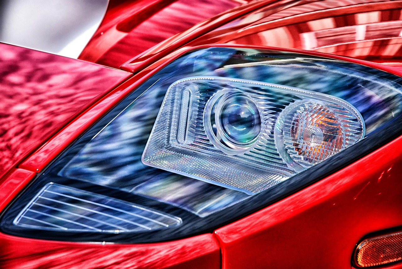 A sports car headlight in razor-sharp close-up against deep red paint