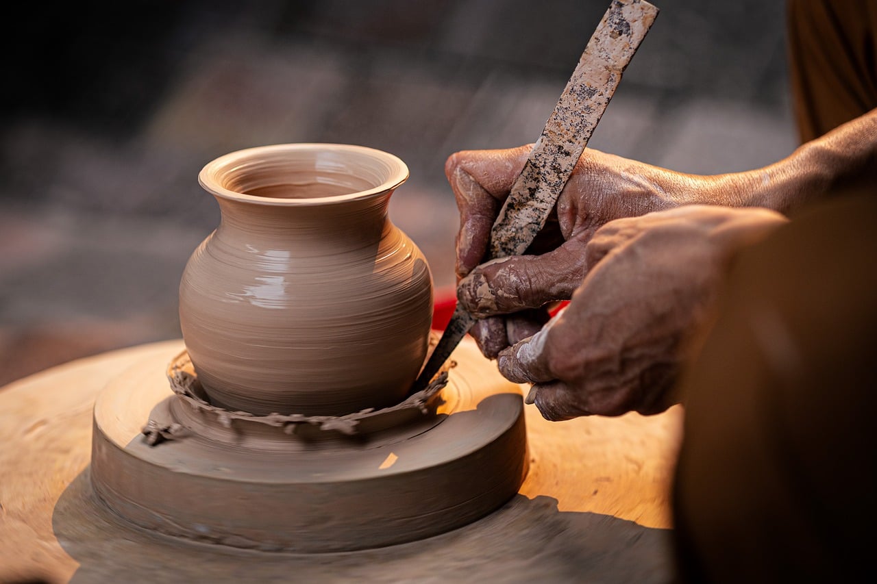 A pot being trimmed with a wooden tool in golden light