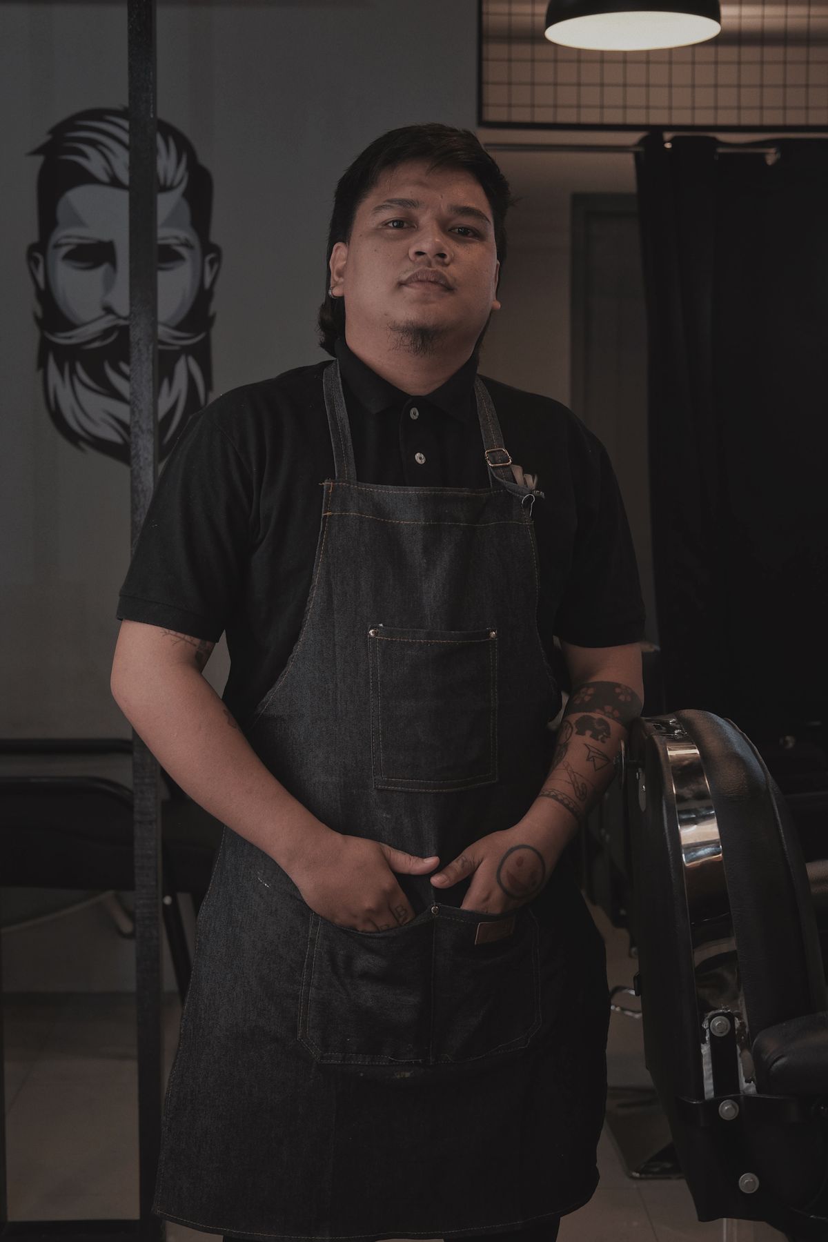 Deniz standing in the shop in a dark apron