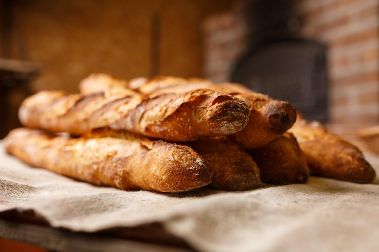 Baguettes stacked on linen in front of the oven