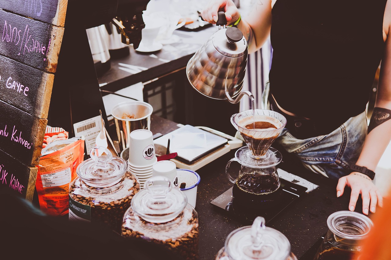 A barista pouring a slow kettle over a brewer
