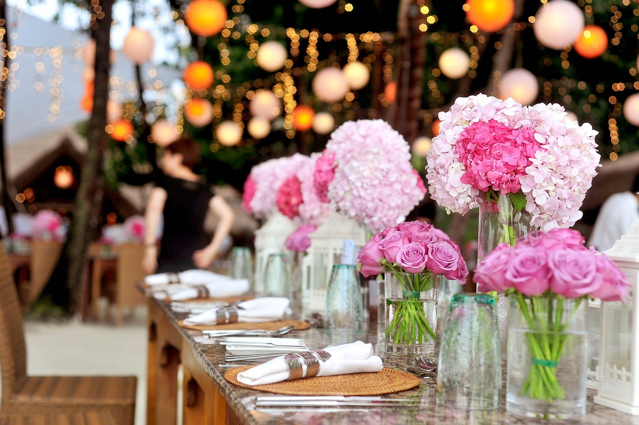 A long reception table under lanterns, pink hydrangeas down the middle