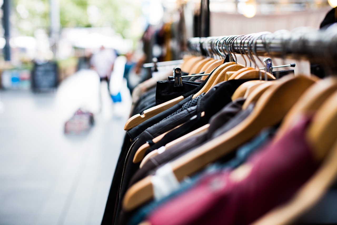 Garments on wooden hangers along a rail