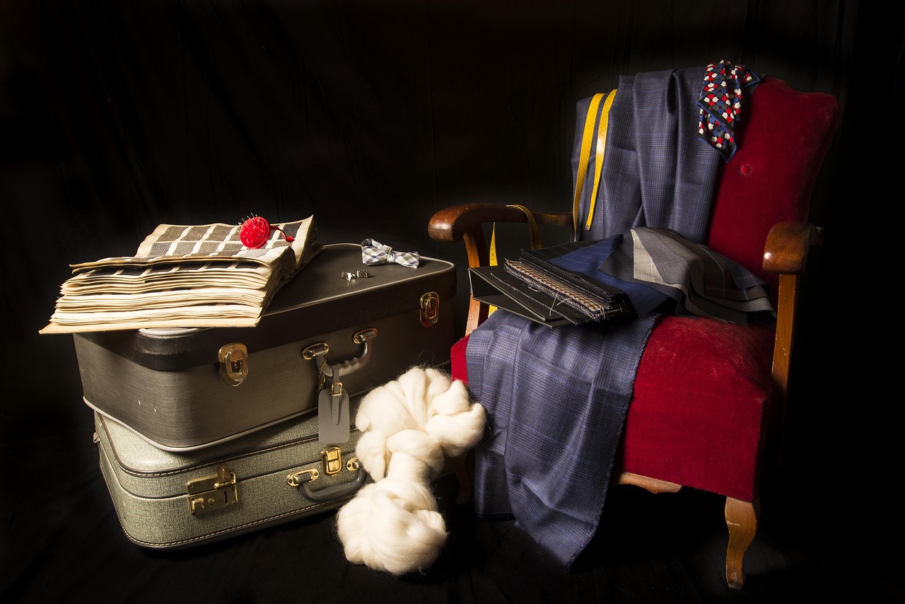 A swatch book resting on vintage suitcases with raw wool