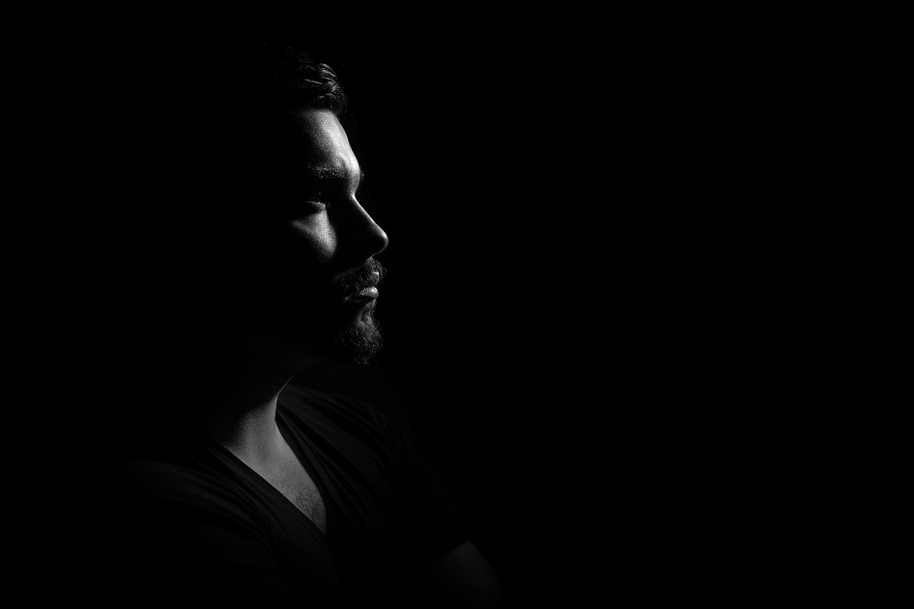 A low-key male profile emerging from darkness