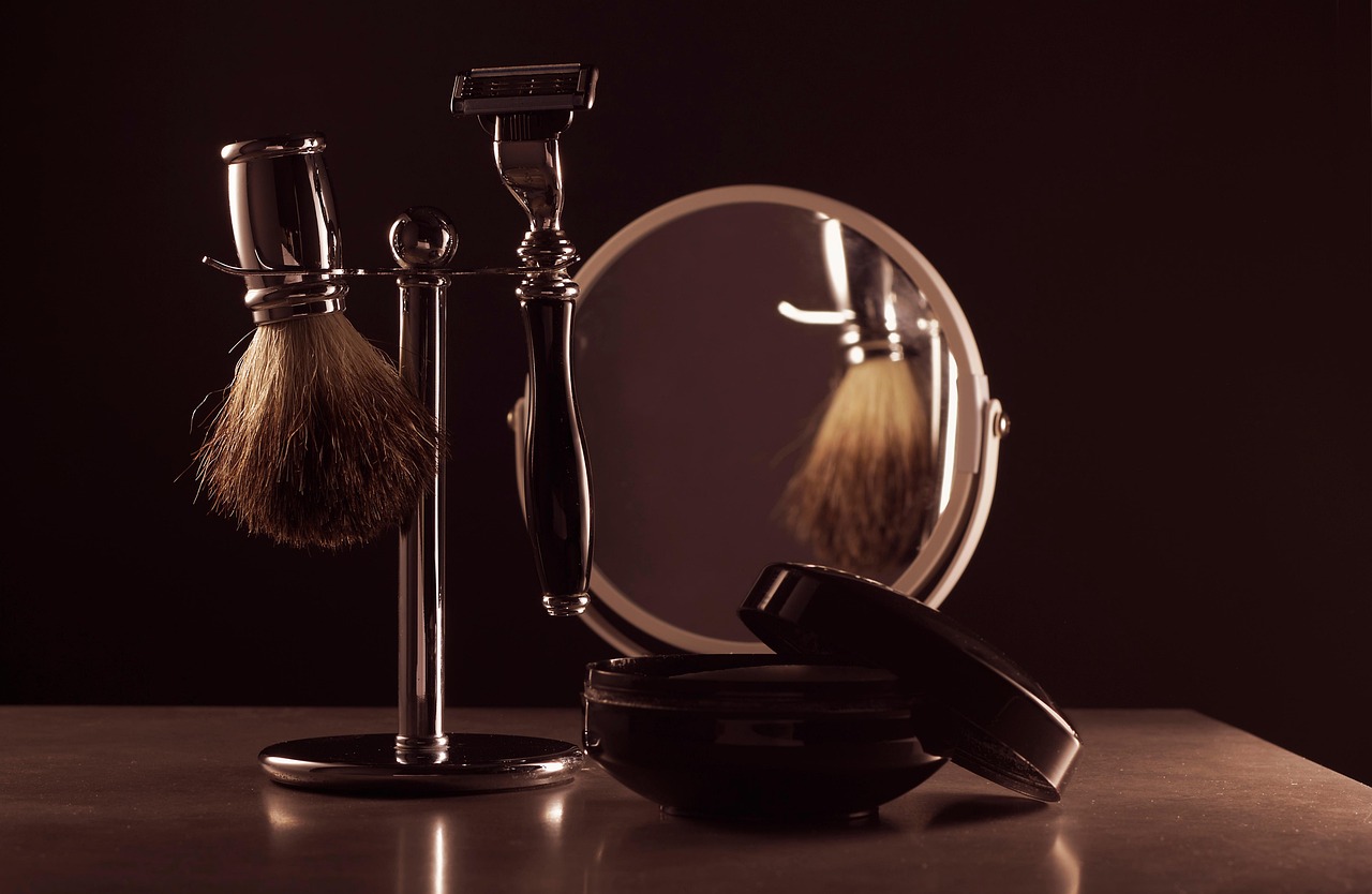 Badger brush, safety razor and mirror on the counter, lit warm against the dark