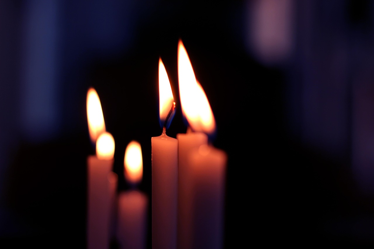 A cluster of lit candles glowing warm against the dark