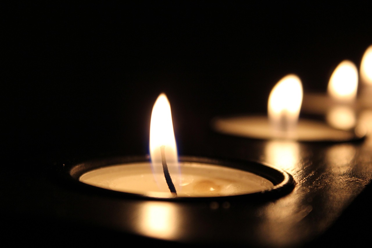 A row of tea lights glowing along dark wood