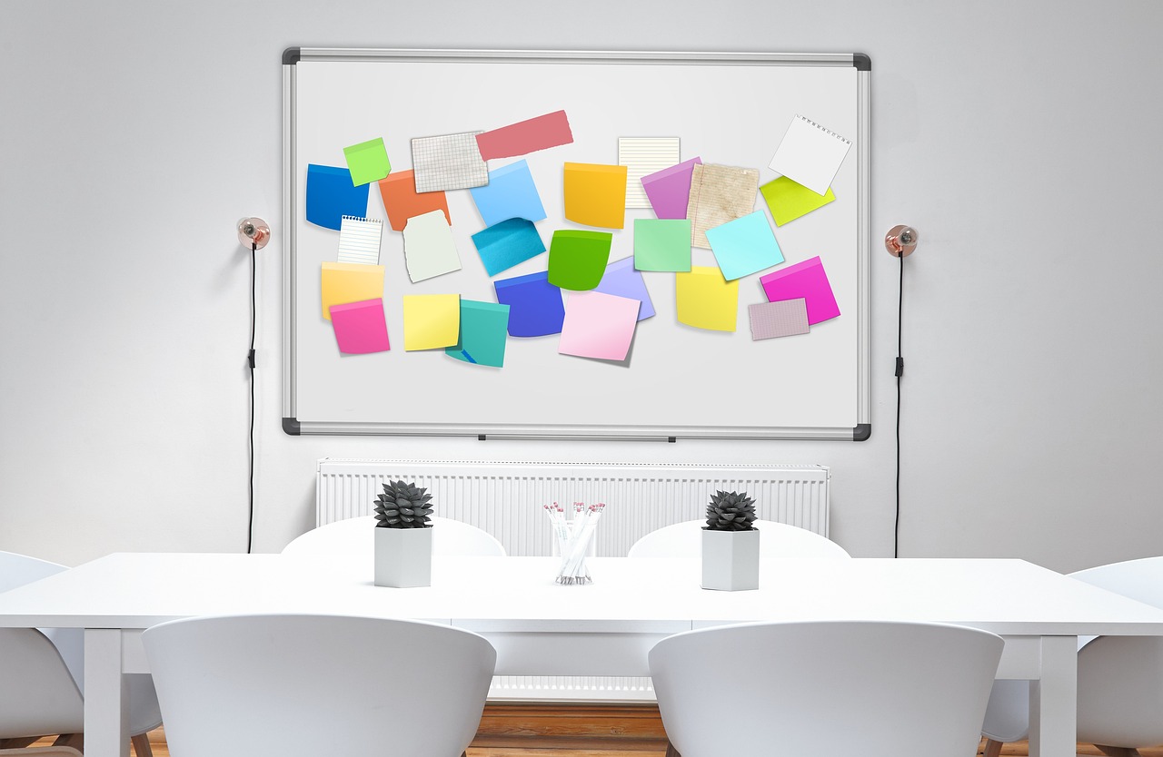 A whiteboard of colourful sticky notes in a bright meeting room