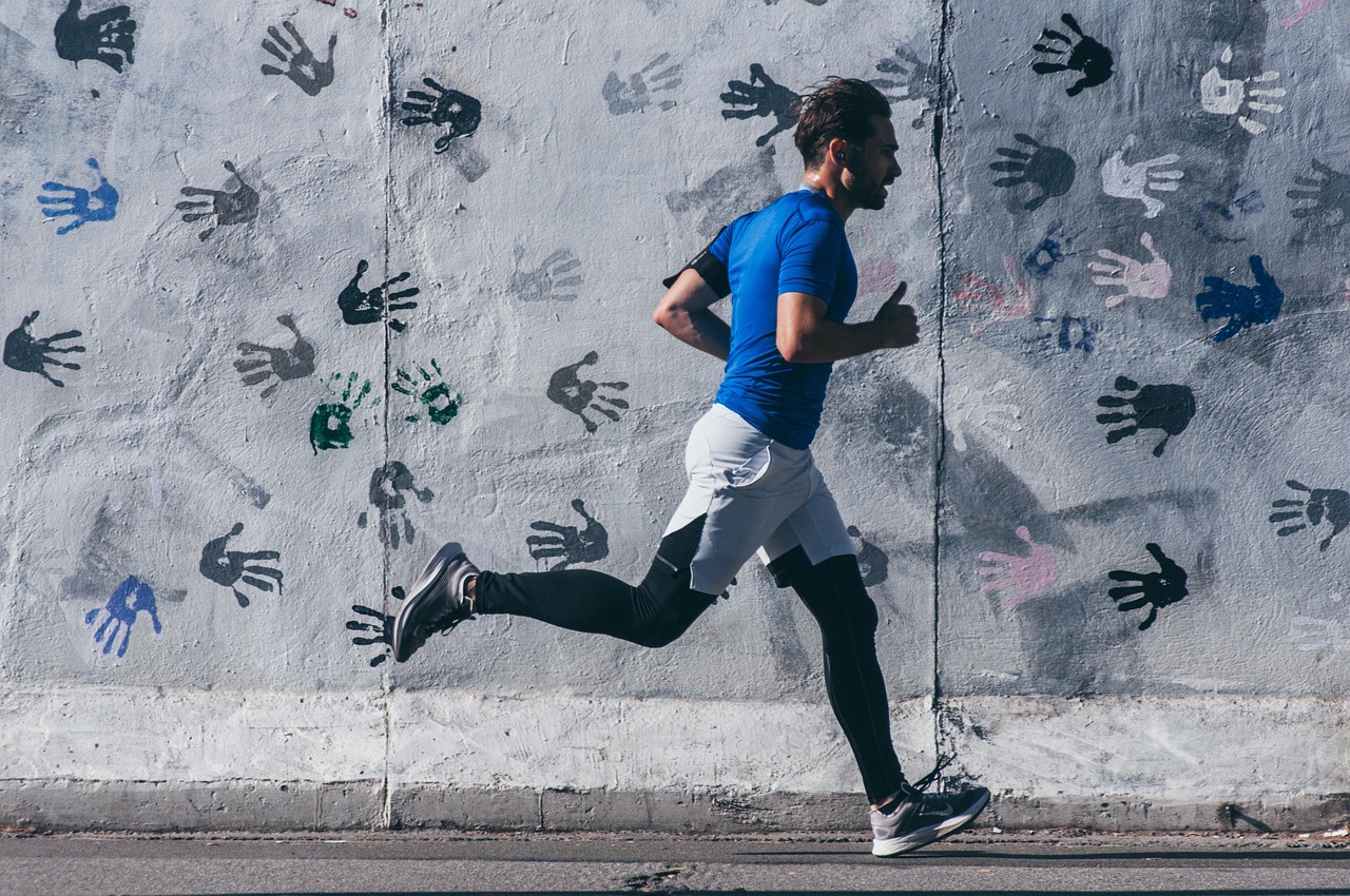 A runner mid-stride past a painted city wall