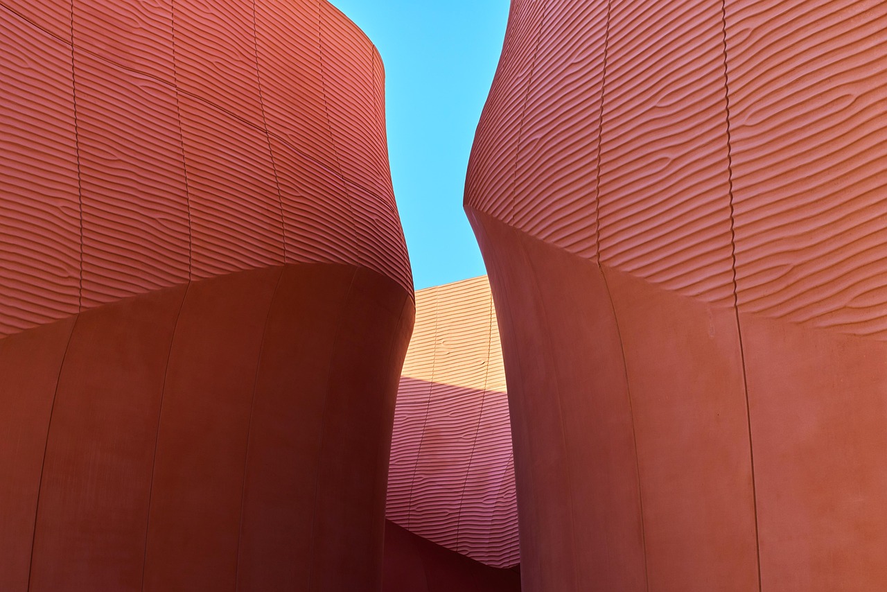 Curved terracotta-red pavilion walls against blue sky